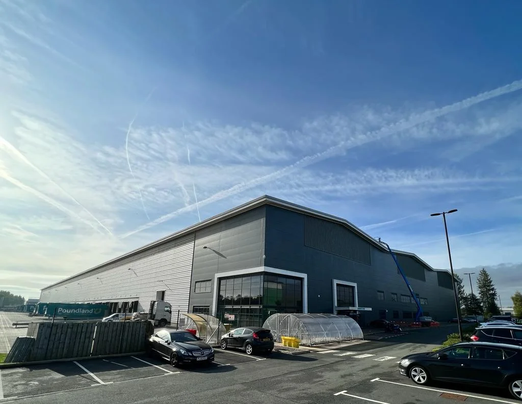 a photograph of a large building with a lot of cars parked in front of it