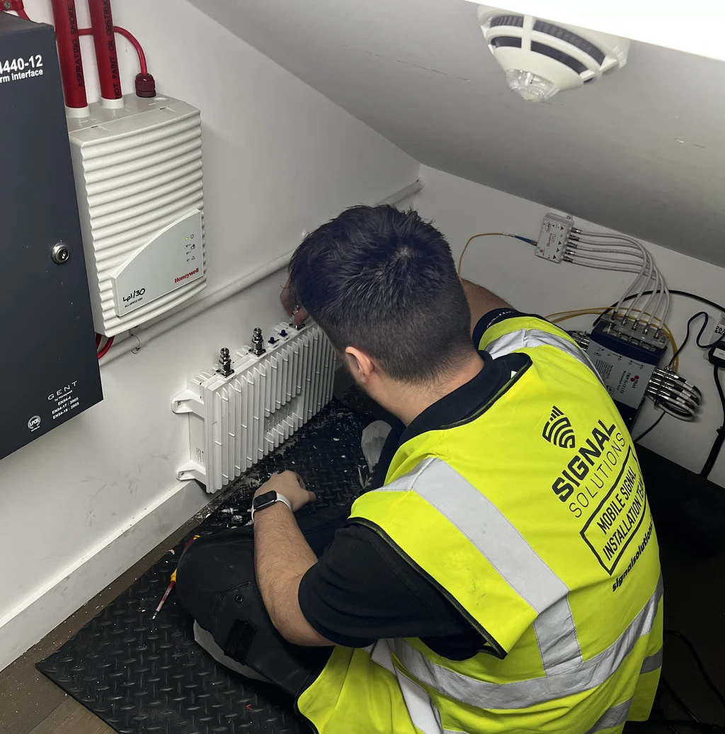 a photograph of a man in a yellow vest is working on a laptop