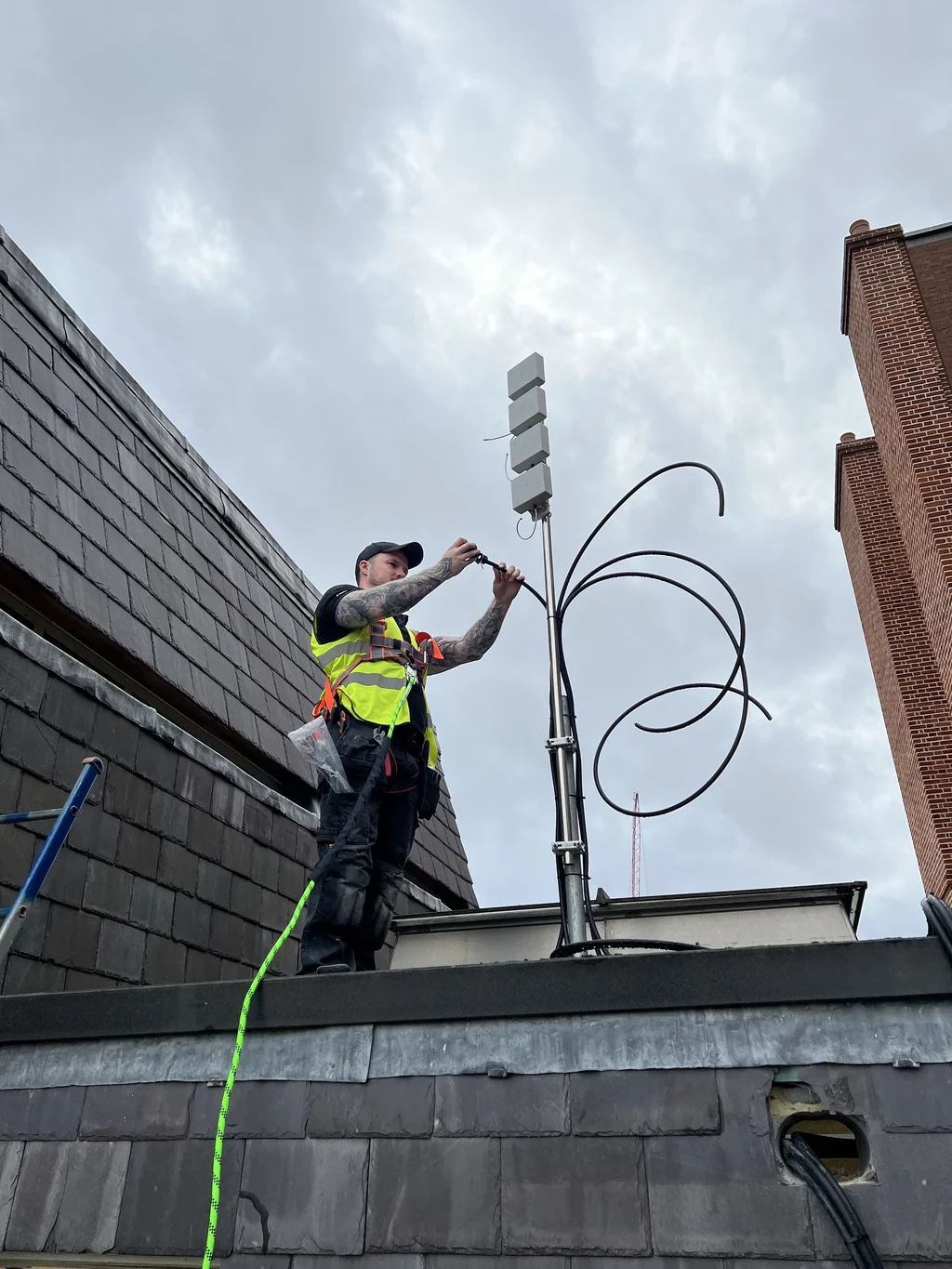 a photograph of a man in a yellow vest is working on a roof