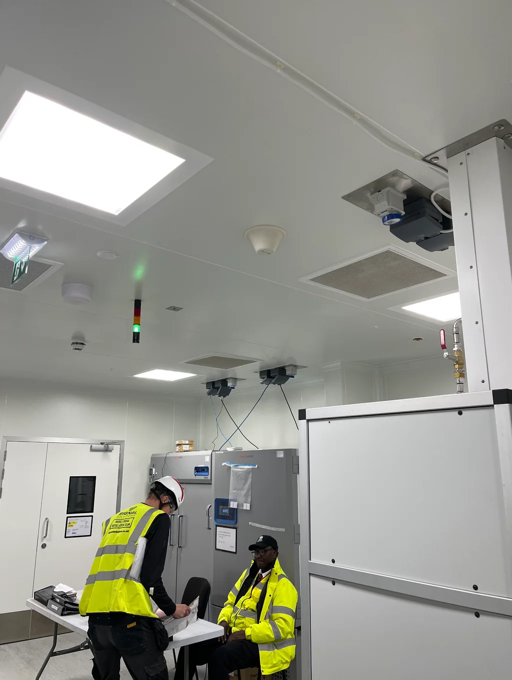 a photograph of two men in yellow vests and safety vests